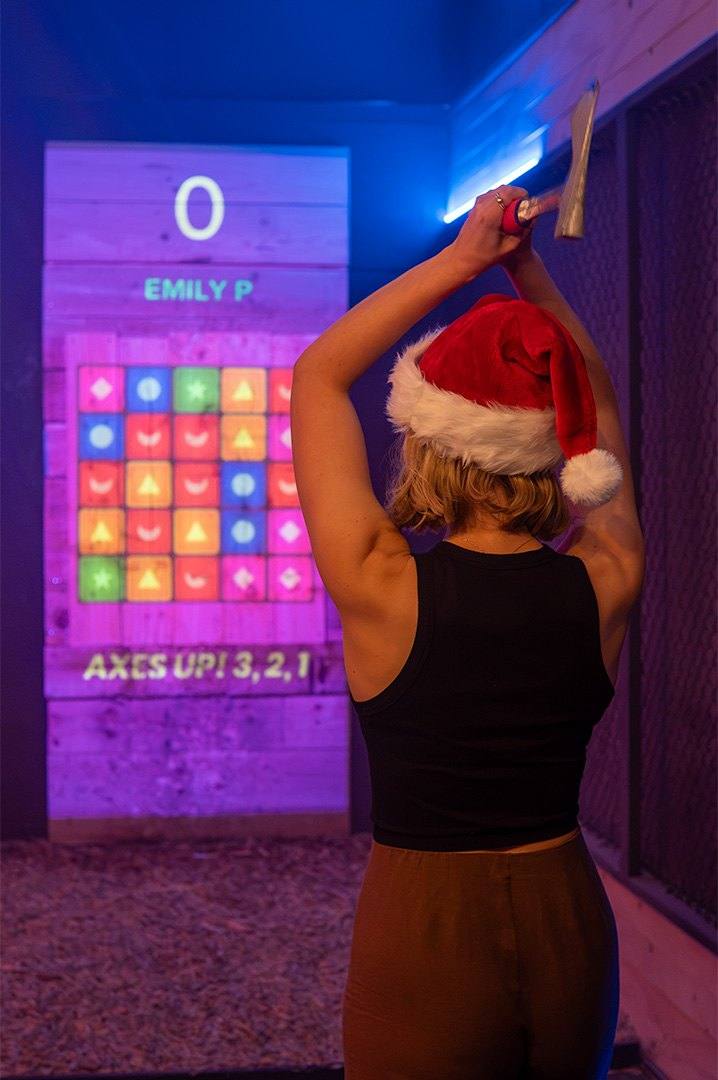Woman in a Santa hat throwing an axe at a digital target