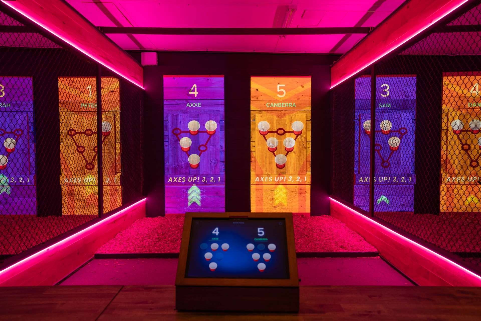 Digital beer pong cups projected onto targets under pink lights