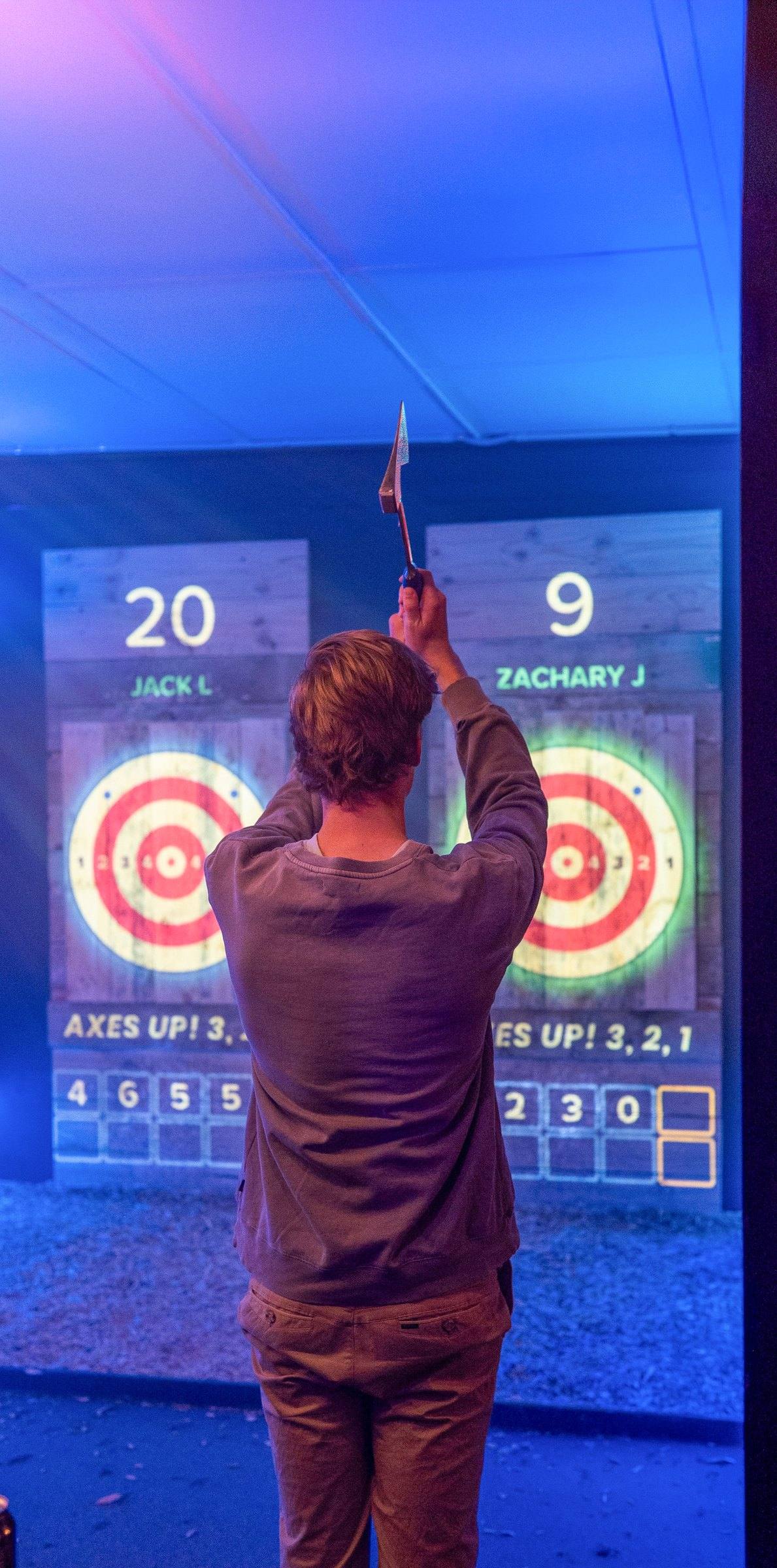 Man throwing an axe at a digital bullseye in a blue-lit lane at Axxe Canberra