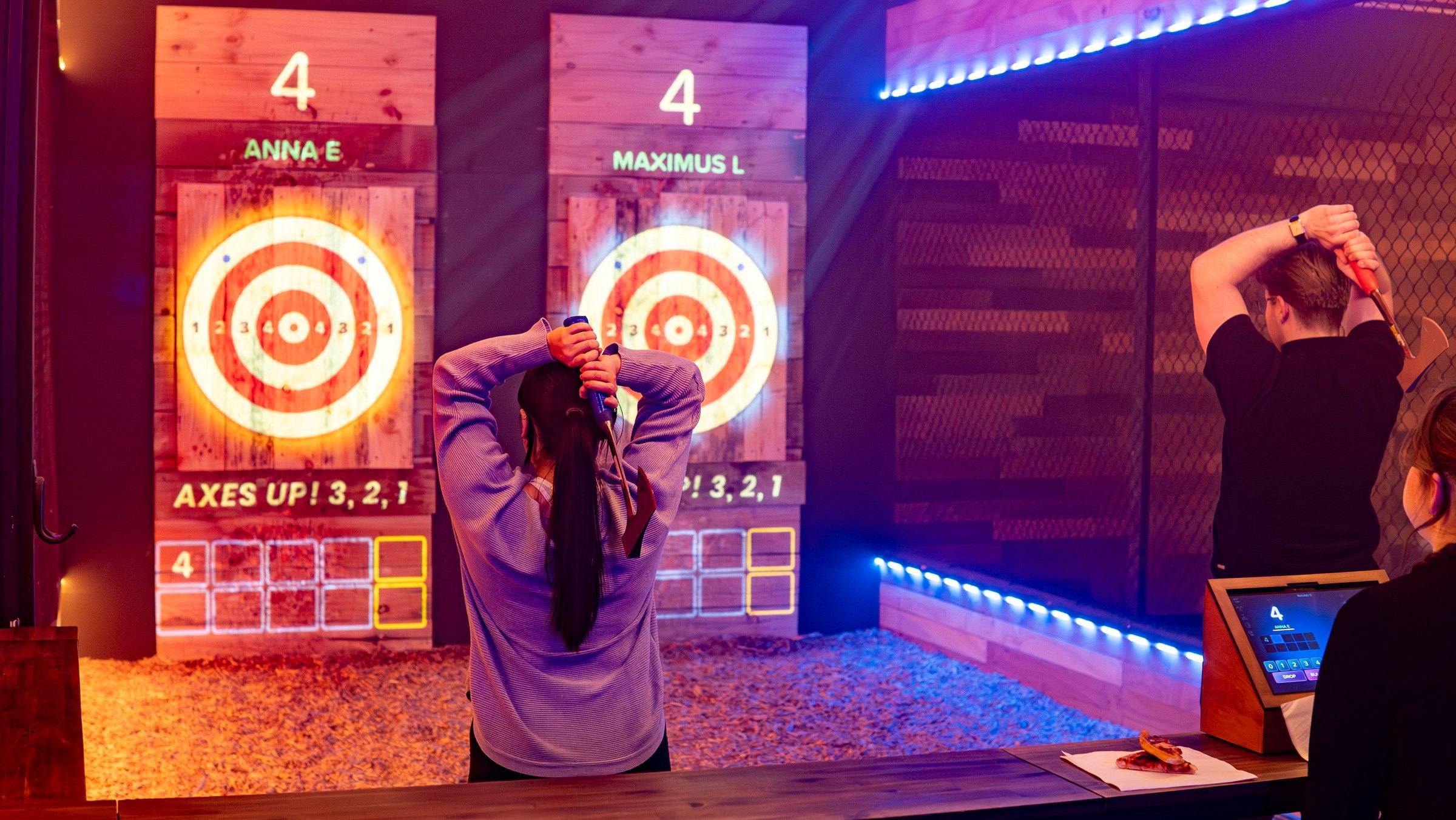 Woman throwing an axe at a glowing red bullseye in a private lane at Axxe