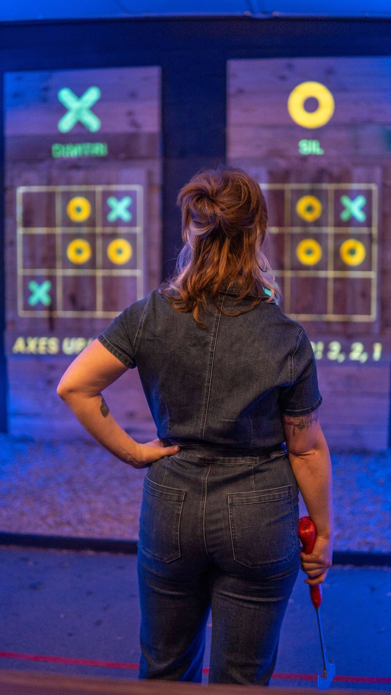 Axe thrower facing a glowing digital tic-tac-toe target at Axxe Canberra